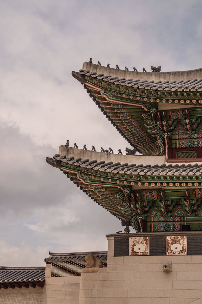 Intricate roof architecture of Gyeongbokgung Palace in Seoul with a cloudy sky.