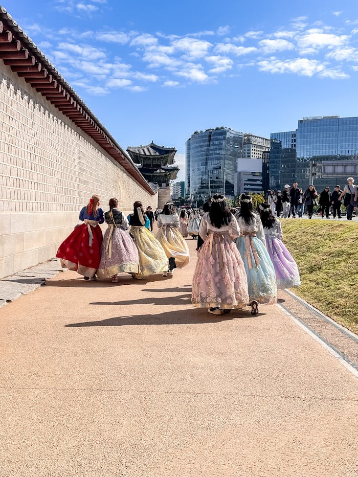 A group of women wearing colorful hanboks walking near Gyeongbokgung Palace in Seoul, South Korea.