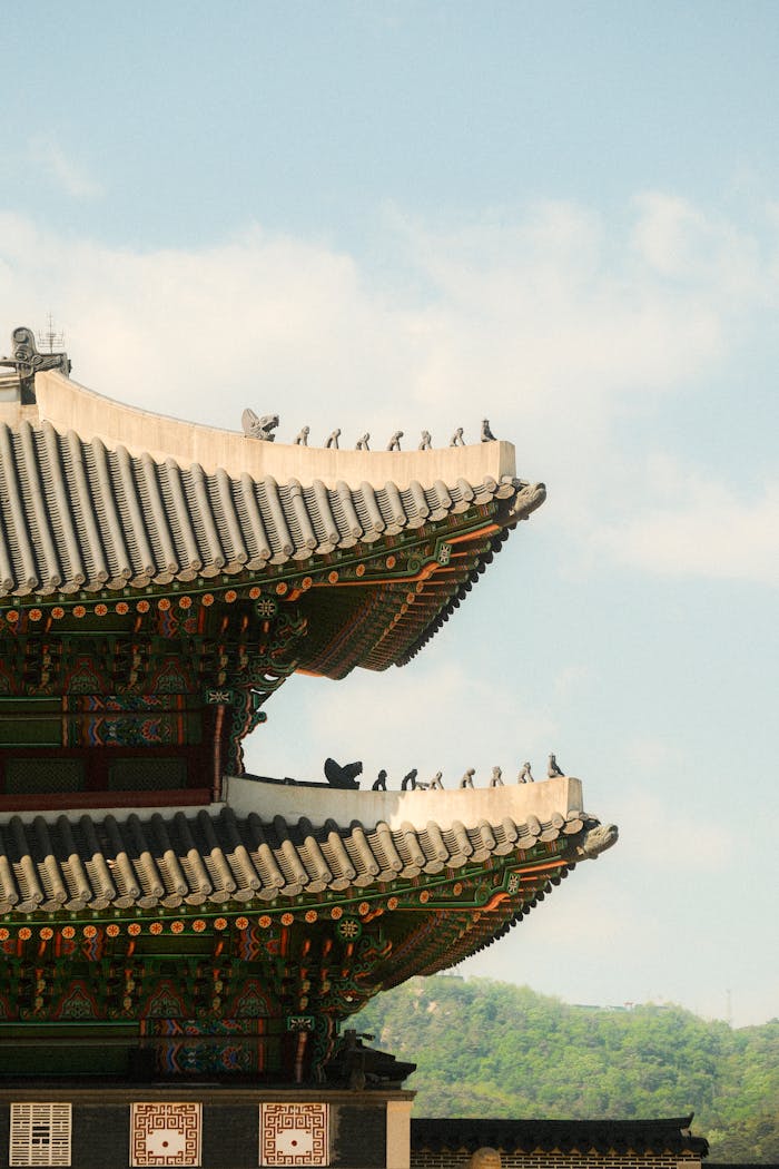 Elegant traditional Korean temple roof structure with ornate details against a blue sky.