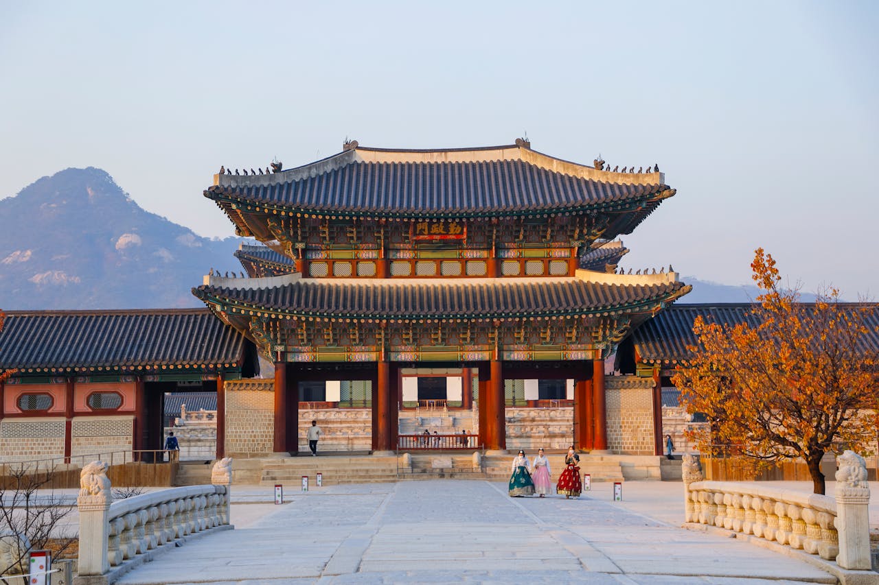 Beautiful view of Gyeongbokgung Palace's traditional architecture with mountains in the background at sunset.